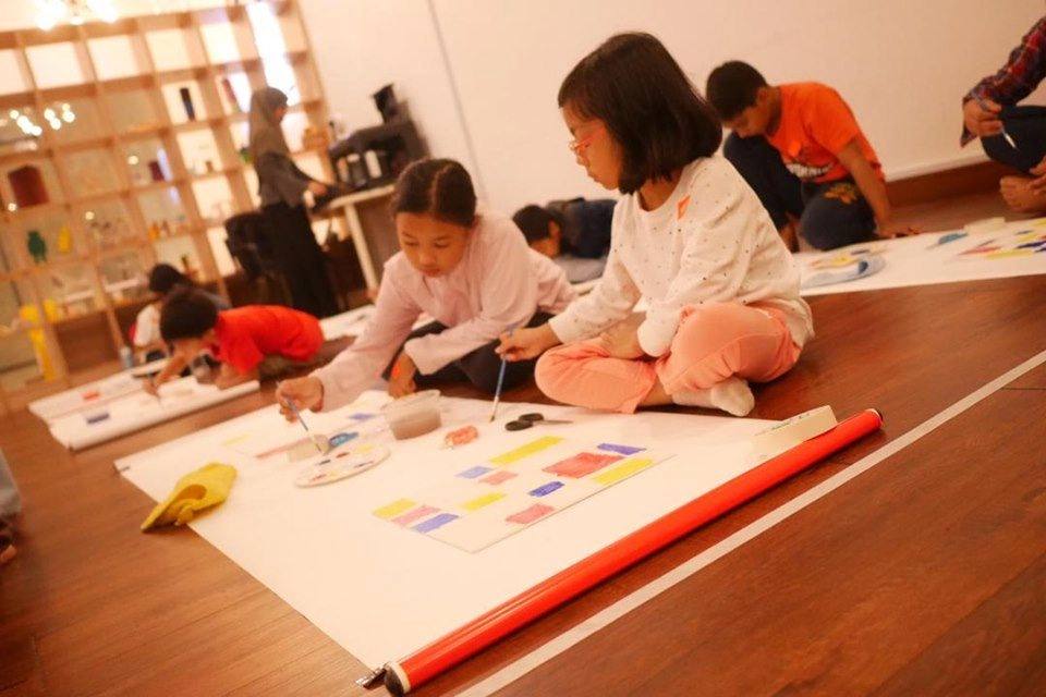 Kids designing a city plan on paper on the floor